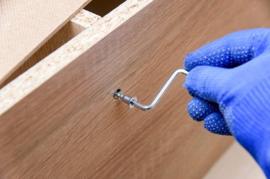 Elin görüntüsü ve tahta mobilya montajı sırasında vida doğrulama. Ev onarım konseptleri. Mobilya fikirleri.