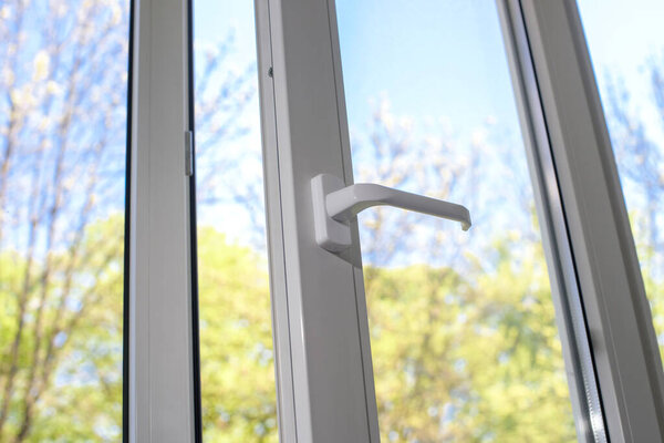 Opened plastic vinyl window. Green leaves background.