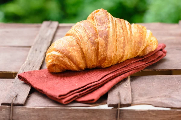 Croissant on brown wood table — Stock Photo, Image