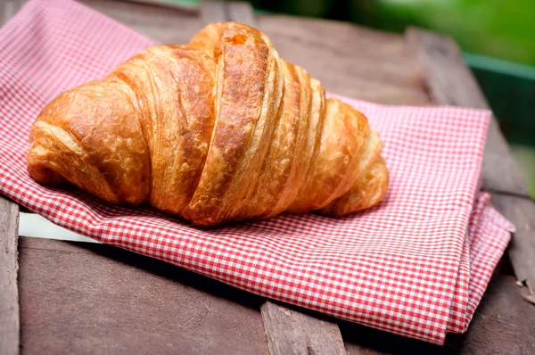 Croissant on brown wood table — Stock Photo, Image