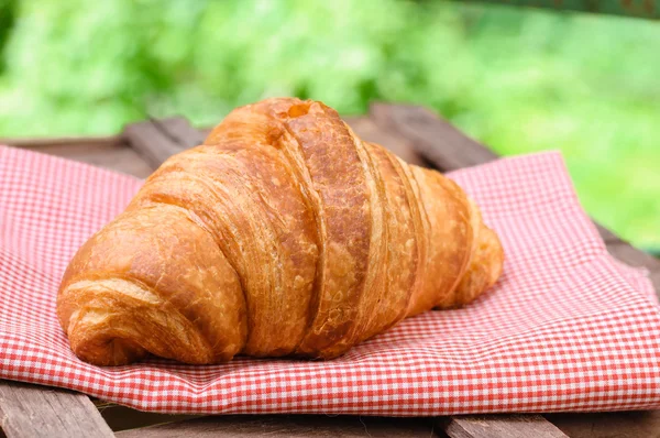 Croissant on brown wood table — Stock Photo, Image
