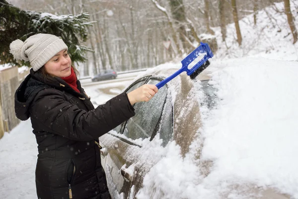 Vrouw reinigt sneeuw auto — Stockfoto