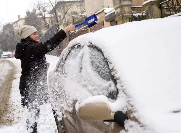 Vrouw reinigt sneeuw auto — Stockfoto