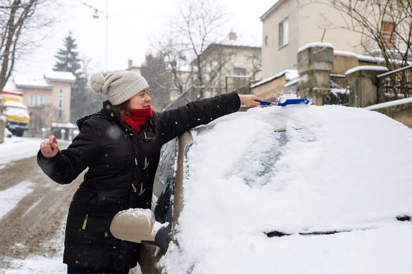 Vrouw reinigt sneeuw auto — Stockfoto