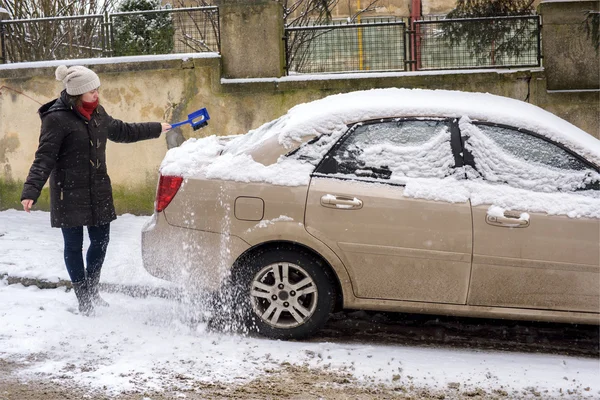 Vrouw reinigt sneeuw auto — Stockfoto