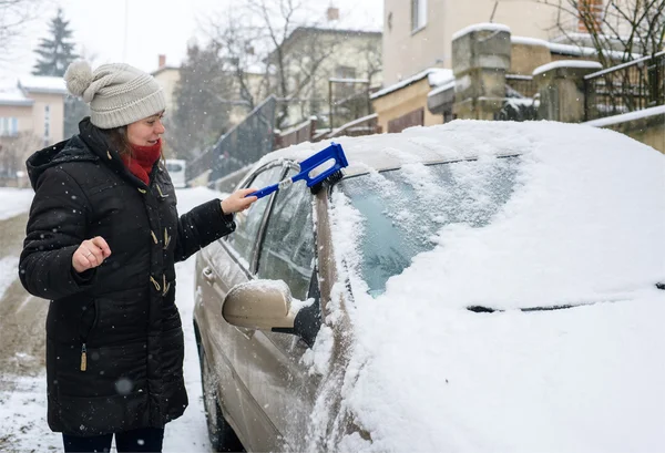 Vrouw reinigt sneeuw auto — Stockfoto