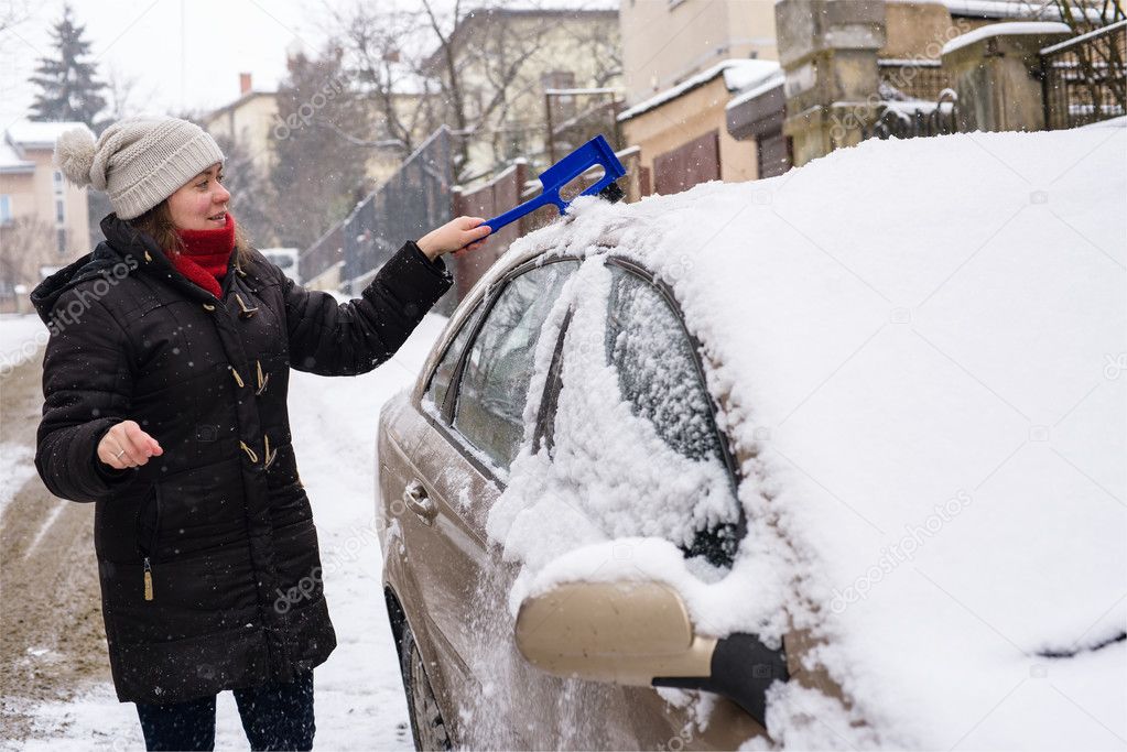 Woman cleans snow car