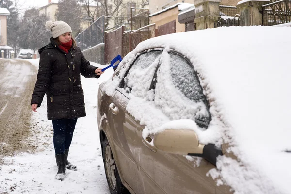 Vrouw reinigt sneeuw auto — Stockfoto