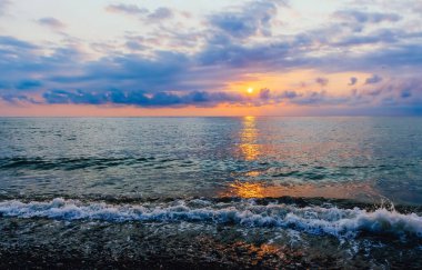 Renkli manzara, bulutlar ve denizde küçük bir dalga.