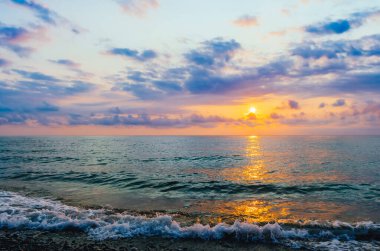 Renkli manzara, bulutlar ve denizde küçük bir dalga.