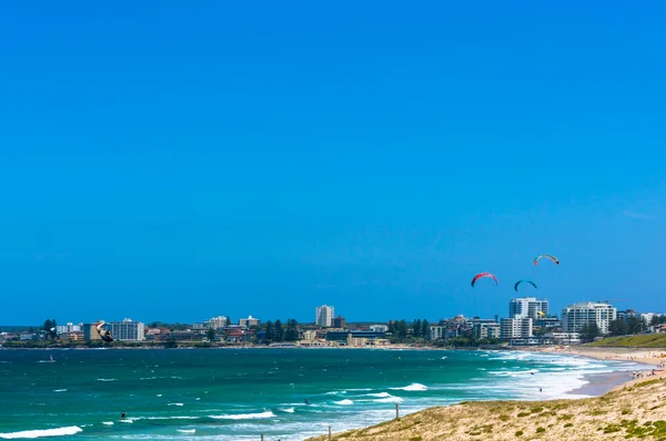 Playa del océano con kite surfers y skyline de la ciudad en una distancia — Foto de Stock