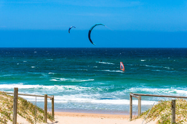 Ocean beach with kite and wind surfers in a distance