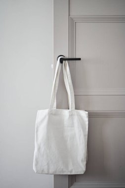 Kapı kolunda beyaz çevre dostu çanta asılı. Çanta çantası.
