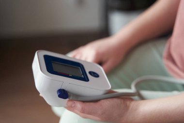 Genç bir kız kan basıncını bir tonometreyle ölçer. 