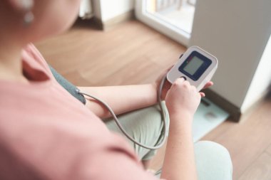 Genç bir kız kan basıncını bir tonometreyle ölçer. 