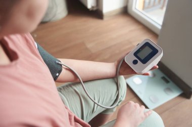 Genç bir kız kan basıncını bir tonometreyle ölçer. 