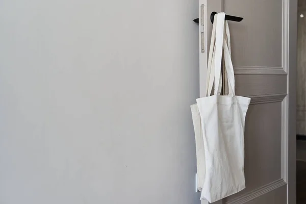 环保概念与白色帆布袋挂在门上 两色色调 环保空白购物袋免费复制空间 减少塑料袋全球变暖 Canvas Tote包 — 图库照片