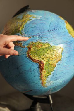 Genç bir kadın, dünyadaki bir ülkeyi işaret ediyor. Rusça dünya yazıtları - ülkelerin ve okyanusların isimleri.