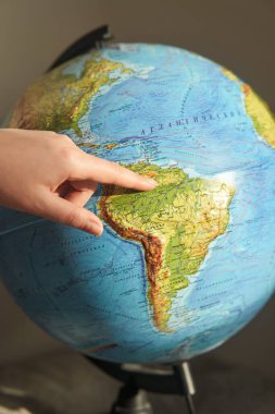 Genç bir kadın, dünyadaki bir ülkeyi işaret ediyor. Rusça dünya yazıtları - ülkelerin ve okyanusların isimleri.