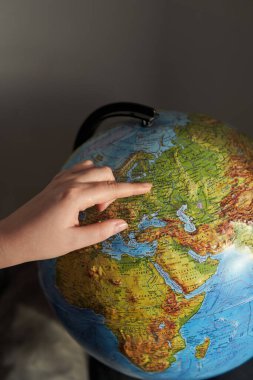 Genç bir kadın, dünyadaki bir ülkeyi işaret ediyor. Rusça dünya yazıtları - ülkelerin ve okyanusların isimleri.