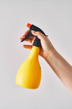 Genç bir kadın elinde bir sprey şişesi tutuyor. Beyaz arka planda sarı sprey şişesi. Yüksek kalite fotoğraf