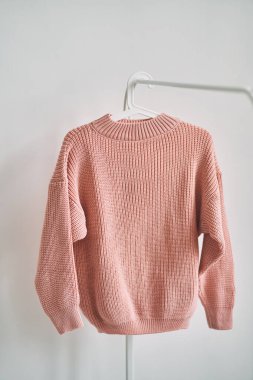 Beyaz arka planda askıda asılı yün bir kazak. Sıcak giysi satışı. Konsept - bir giyim mağazasında her şey satılır..