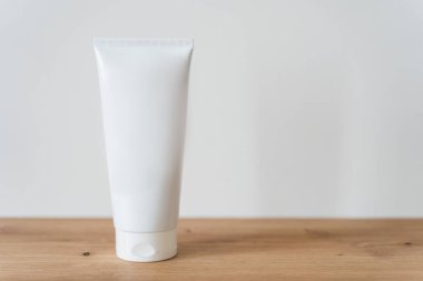 Beyaz tüp krem, ahşap bir masanın üzerinde..