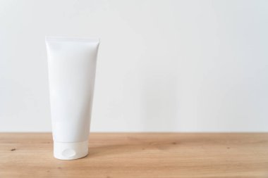 Beyaz tüp krem, ahşap bir masanın üzerinde..