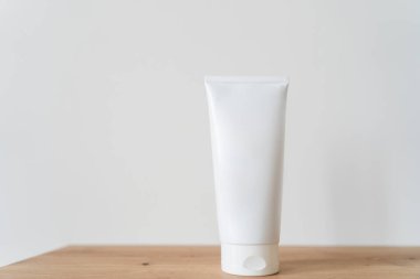 Beyaz tüp krem, ahşap bir masanın üzerinde..