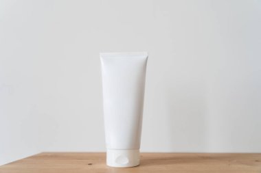 Beyaz tüp krem, ahşap bir masanın üzerinde..