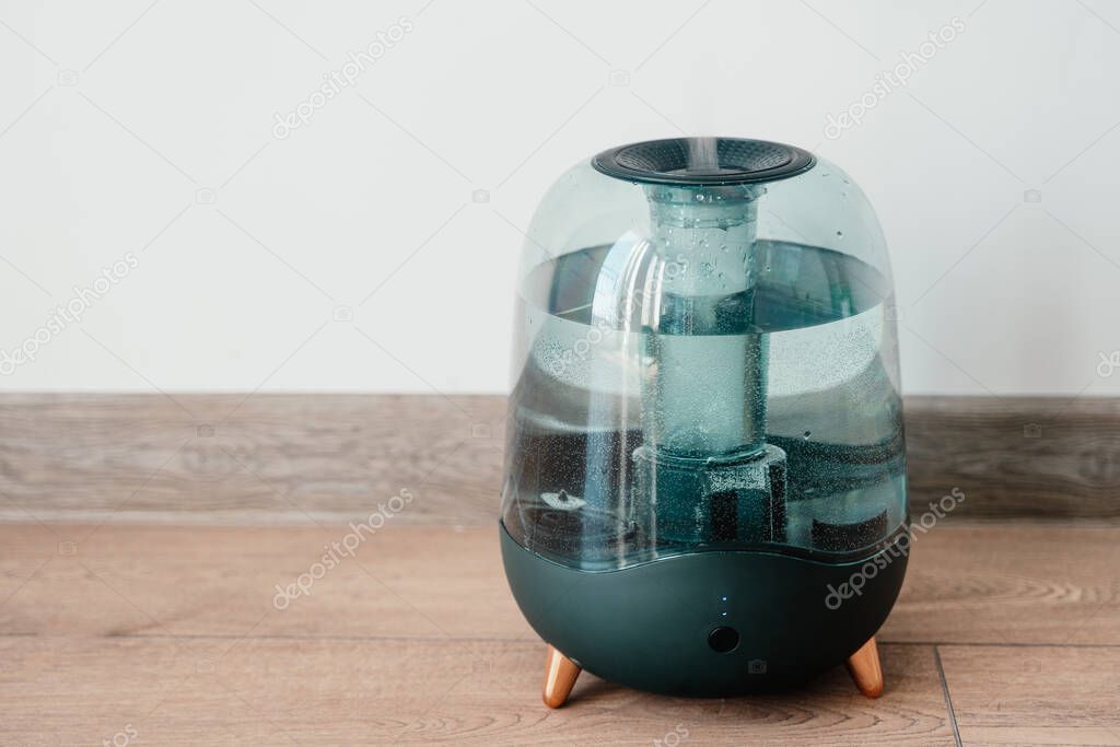 Modern air humidifier on a white wall background. Humidifier spreading steam into the living room.