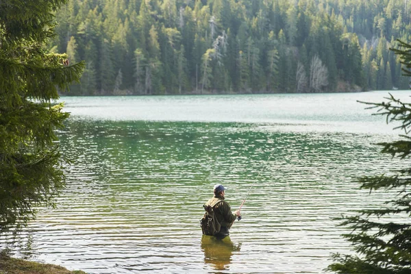 Fisher man stands in the water and catch fish in the lake on a background of mountains. High quality photo