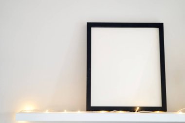 Beyaz arka planda içi boş ahşap fotoğraf çerçevesi duruyor. Model poster çerçevesi evin içini kapatıyor. Yüksek kalite fotoğraf