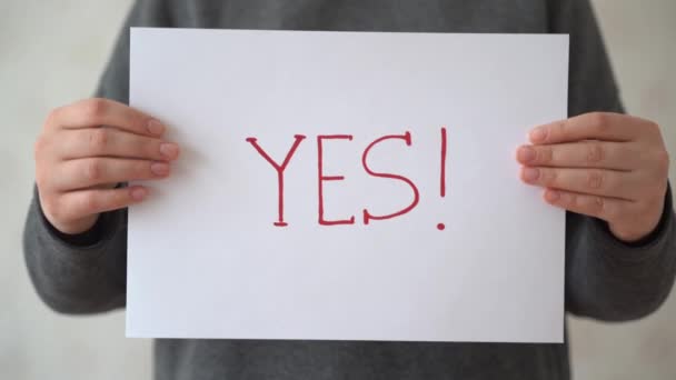 若い女性は「 YES 」という言葉で白い紙を持っています。 — ストック動画