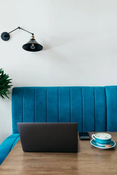 Masadaki büyük bardakta, telefonlu modern bir laptop ve bir fincan kibrit kahve. Serbest çalışmak için şık bir kafe. Boşluğu kopyala