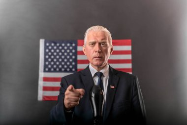 2020 Amerikan başkanlık seçimleri koyu bir arka planda Amerikan bayrağı, olgun gri saçlı bir adam, bir karakter, bir aktör, bir demokrat duygusal jestler yapan ve bir münazarada parmağıyla işaret eden.