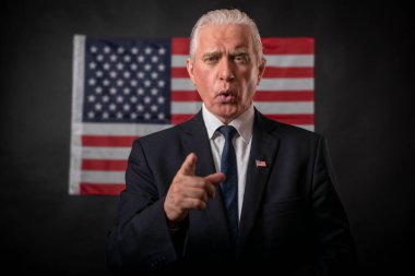 2020 Amerikan başkanlık seçimleri koyu bir arka planda Amerikan bayrağı, olgun gri saçlı bir adam, bir karakter, bir aktör, bir demokrat duygusal jestler yapan ve bir münazarada parmağıyla işaret eden.
