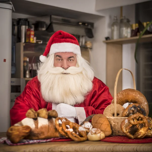 Jultomten i köket behandlar välsmakande bullar Stockfoto