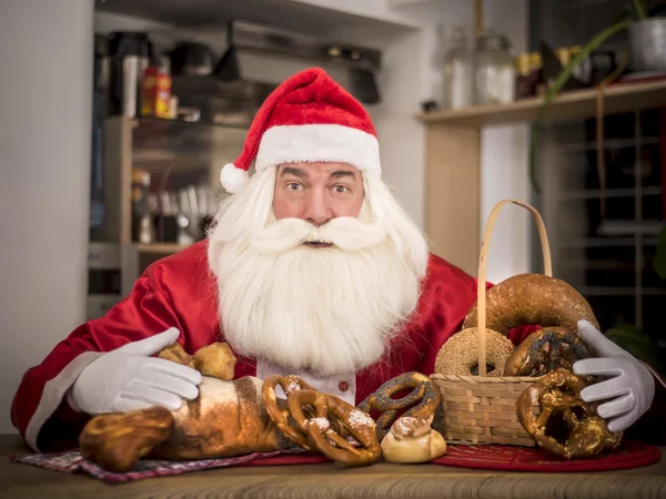 Jultomten i köket behandlar välsmakande bullar Royaltyfria Stockbilder