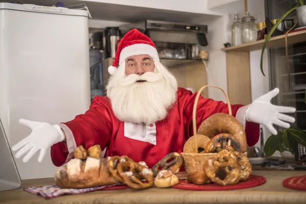 圣诞老人在厨房里对待美味面包 免版税图库照片