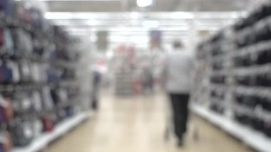 Blurred people walking in supermarket with shopping cart. Rows in the supermarket.