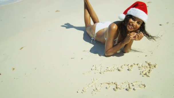 Mladá dívka, která nosí klobouk Santa na pláži — Stock video