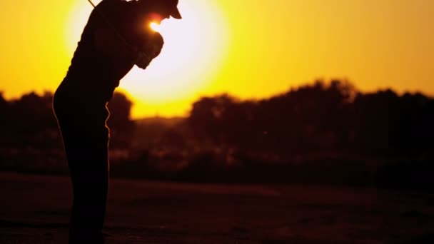 Чоловічий гольф грає в гольф на заході сонця — стокове відео
