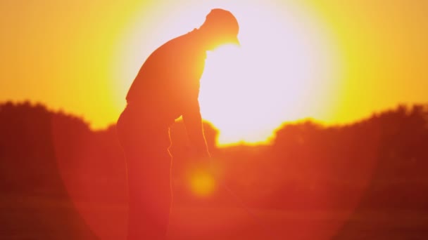 Golfista masculino jogando golfe ao pôr do sol — Vídeo de Stock