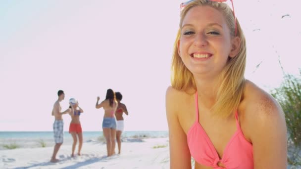 Dziewczyna siedzi na plaży, a przyjaciele grać w piłkę — Wideo stockowe