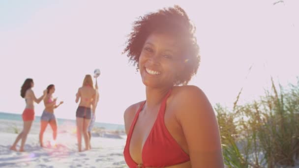 Menina sentada na praia enquanto amigos jogar bola — Vídeo de Stock