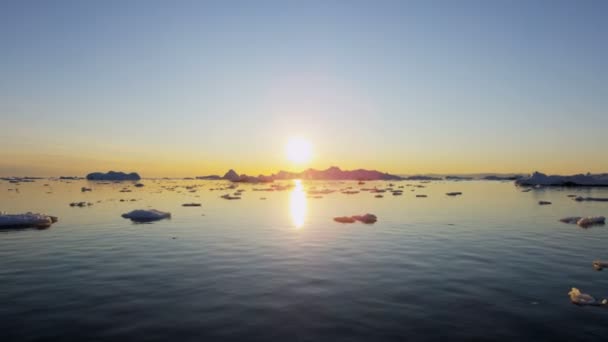 Témpanos glaciares flotando en el agua al atardecer — Vídeos de Stock