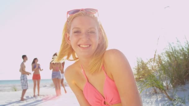 Girl sitting on beach while friends play ball — Stock Video