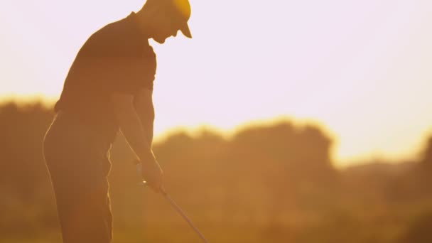 Golfista masculino jugando al golf al atardecer — Vídeo de stock