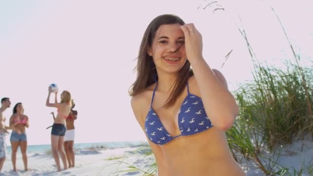 Girl sitting on beach while friends play ball — Stock Video